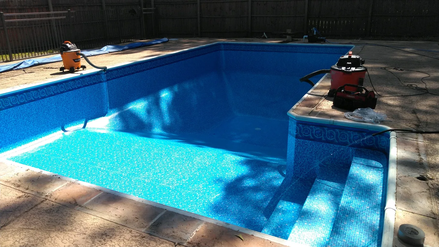 Blue liner being fitted with work equipment around the pool
